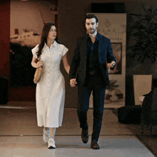 a man in a suit and a woman in a white dress are walking in front of a sign that says alaz massage