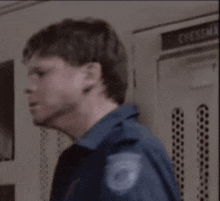 a man in a blue shirt is standing in a locker room with his eyes closed