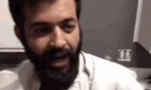 a man with a beard is wearing a lab coat and headphones .