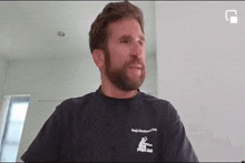 a man with a beard is wearing a black shirt .