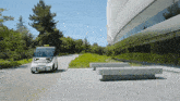 a small white vehicle with a license plate that says ' california ' on it drives down a road