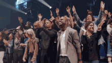 a group of people are standing in a line with their hands in the air