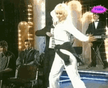 a woman is dancing on a stage with a pink sticker in the background