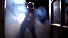 a man in a mask is standing in a dark room with smoke coming out of the door