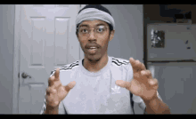 a man wearing a headband and an adidas shirt is making a funny face