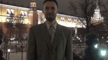 a man in a suit stands in front of a building with a clock tower