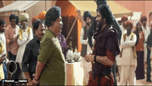 a man in a turban is talking to another man in a crowd with the words pranay varma on the bottom