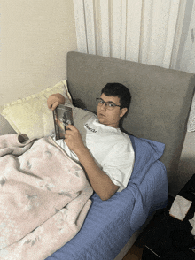 a young man laying on a bed holding a book that says ' genesis ' on the cover