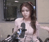 a woman wearing headphones is standing in front of a microphone .