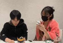 a man and a woman are sitting at a table and the woman is wearing a mask .