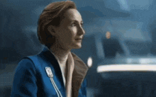 a woman in a blue jacket is sitting in front of a train .