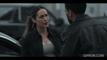 a man and a woman are having an argument in front of a car with the website gifrun.com in the corner