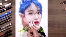 a drawing of a woman with blue hair is on a table with pencils