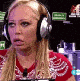 a woman wearing headphones and a red shirt is sitting in front of a sign that says salida de emergencia .