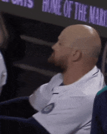 a bald man sitting in front of a screen that says home of the mariners