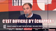 a man is speaking into a microphone with the words c'est difficile d' y echapper