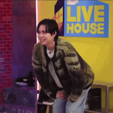 a young man is standing in front of a live house sign