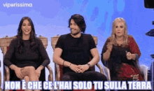 a man and two women are sitting next to each other on a stage .
