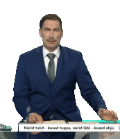 a man in a suit and tie is standing in front of a sign that says " kuused truppa "