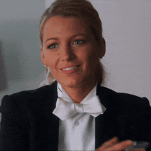 a woman wearing a tuxedo and bow tie smiles for the camera