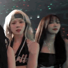 two women are standing next to each other in a dark room and looking at the camera .