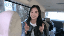 a woman is giving a thumbs up in a car with a 9 block sign in the background
