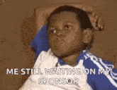 a young boy is sitting on a couch with his hands on his head and a caption that says `` me still waiting on my sponsor ''