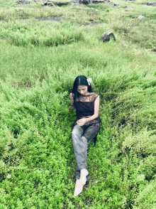 a woman in a black dress is laying on the grass