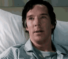 a man is laying in a hospital bed with his eyes closed .