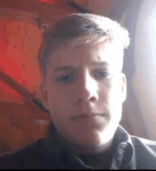 a close up of a young man 's face with a red background