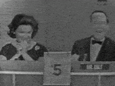 a man and a woman sitting at a table with a sign that says $ 5 on it