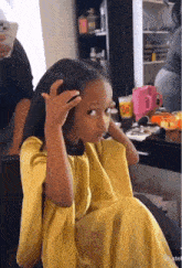 a little girl in a yellow dress is sitting in a chair