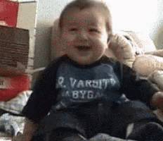 A baby laughing hard, falling sideways