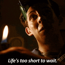 a man holding a candle with the words life 's too short to wait