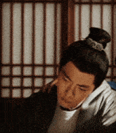 a man with a bun on his head looks down at something