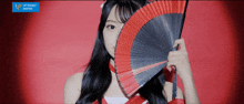 a girl is holding a fan in front of her face with a blue sign that says upfront