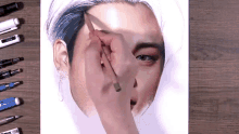 a drawing of a person 's face is being drawn by a person with a pencil and a pen