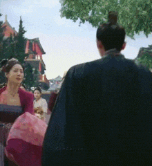 a man and a woman are standing next to each other in front of a tree .