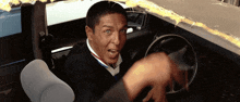 a man sitting in a car with his mouth open and a steering wheel in front of him