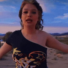 a woman wearing a black one shoulder top with the word ed hardy on the front