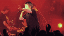 a man singing into a microphone in front of a crowd with the letter d on the bottom right