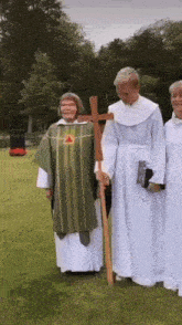 a group of priests are standing in a grassy field holding a cross