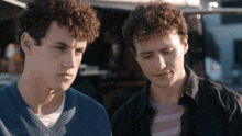 two men are standing next to each other and looking at something