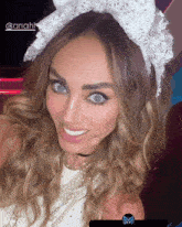 a woman wearing a white lace headband and pearls is smiling