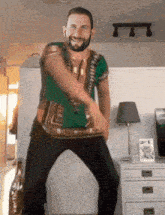a man in a green shirt and black pants is dancing in a living room