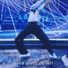 a man is jumping in the air on a stage with the words `` baila si sos de lari '' .
