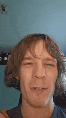 a man with long hair and a beard is making a face with his eyes closed