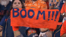 a woman is holding a banner that says boom !!! in a crowd of people .