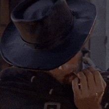 a man wearing a cowboy hat is smoking a cigarette .