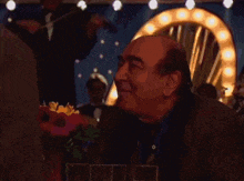 a man sitting at a table with glasses and flowers in front of him